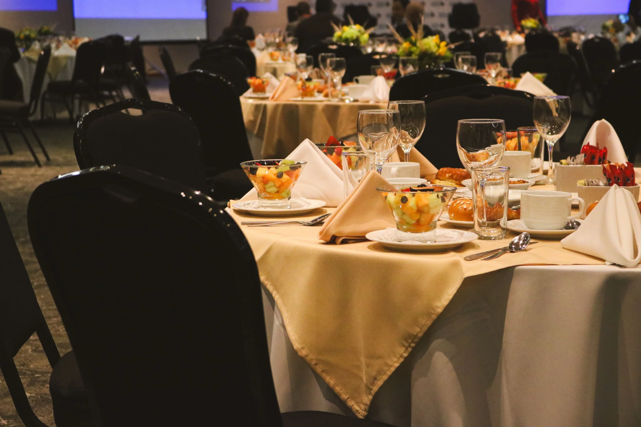 Round banquet table set with fruit cups, pastries, coffee and folded napkins at a corporate event