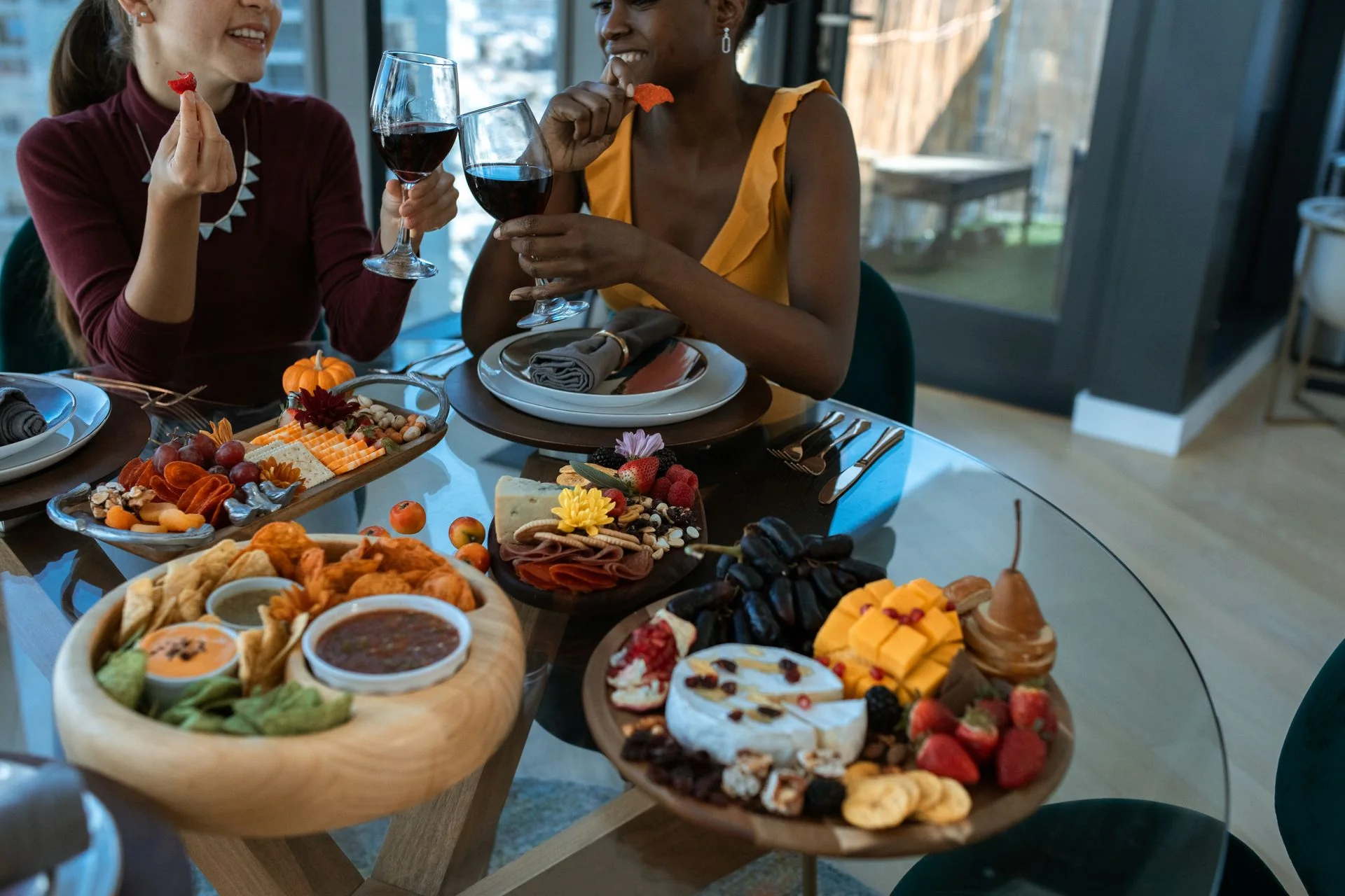 Friends sharing wine around boards of cheese, fruit and dips